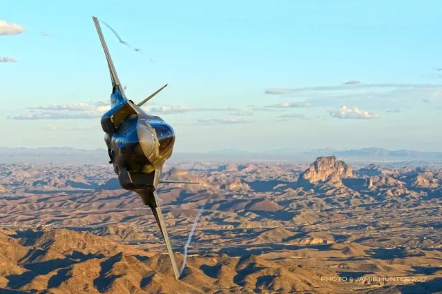 A military aircraft flying over the desert