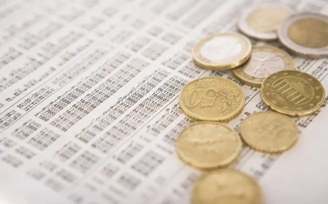 Euro coins on top of paper with numbers and dates on