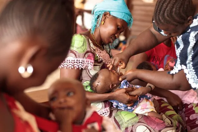 An African healthcare worker treating a baby with its mother