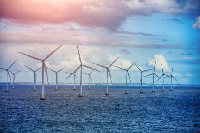 Wind farm at sea with land in the distance
