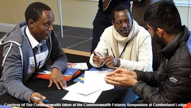 Three men sat around a table in conversation