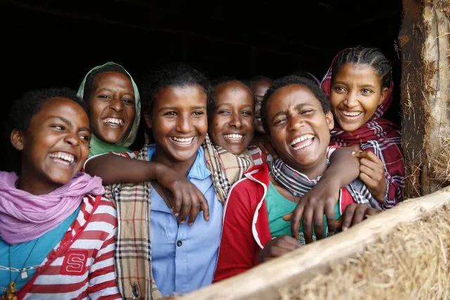 A group of girls stand together, embracing and smiling,