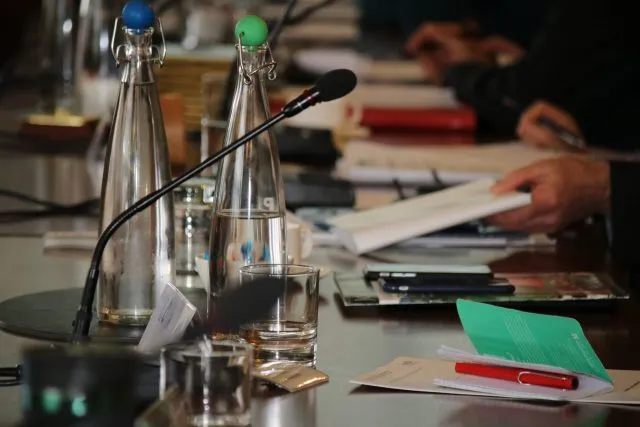 Water bottles, glasses and paperwork on the conference room table at Wiston House