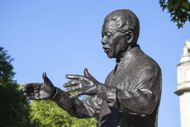 A bronze statue of Nelson Mandela with his arms outstretched.
