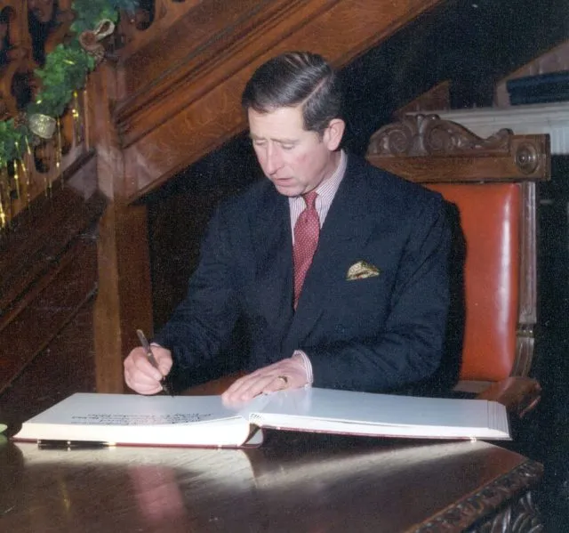 King Charles III signs the guest book at Wilton Park.