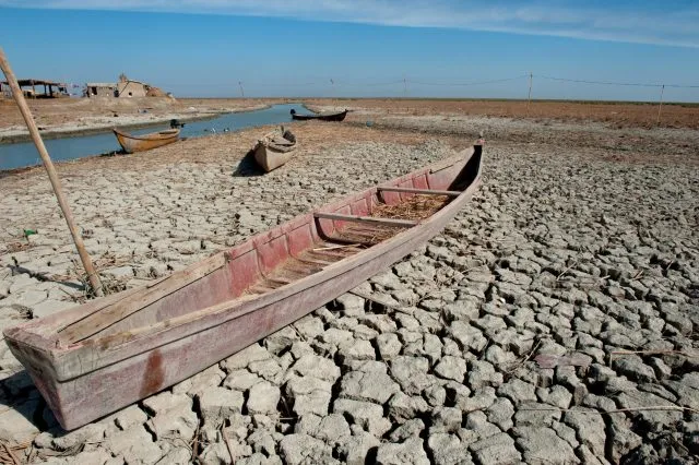 A traditional Marsh Arab canoe known as a Mashoof abandoned on the dry earth of the southern marshes of Iraq during a harsh summer drought.