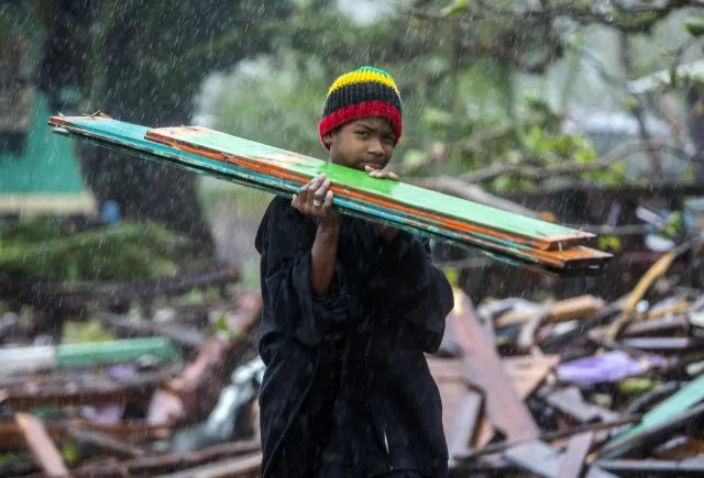 A child carries scraps of wood to help their parents rebuild their home after it was destroyed by the strong winds and rains brought by Hurricane Iota in Nicaragua, in Bilwi, on November 17, 2020.