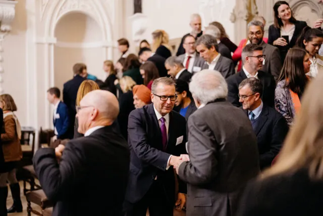 Participants greeting each other in the Great Hall at Wilton Park in December 2023.