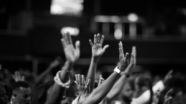 People raise their hands in a crowd