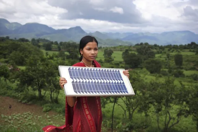 Meenakshi Dewan age 20, from the village of Tinginapu, in the Eastern Ghats, Orissa, holds a solar panel against a backdrop of green hills