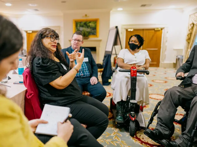 Pamela Molina Toledo, Executive Director of the World Federation of the Deaf, signs during a breakout group, watched by Juan Angel Juan Angel de Gouveia, President of the Latin American Network of NGOs of Persons with Disabilities and Their Families (RIADIS), and Lizzie Kiama, founder of This Ability Kenya.