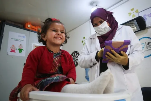 A nurse weighs a small child
