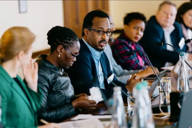 Participants sit along the conference room table