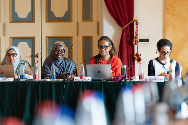 Faith for our Planet Youth Ambassador Fariah Lalaikipian, sits with Liliane Nkunzimana, Representative of the Baha'i International Community to the United Nations, at the conference table.