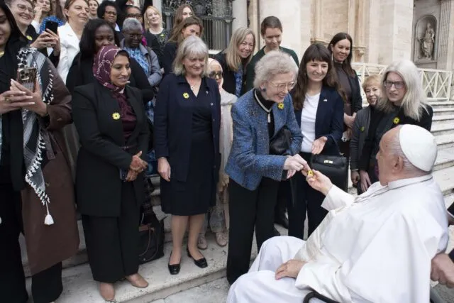 Mary Robinson hands Pope Francis a yellow dandelion badge, symbol of Project Dandelion