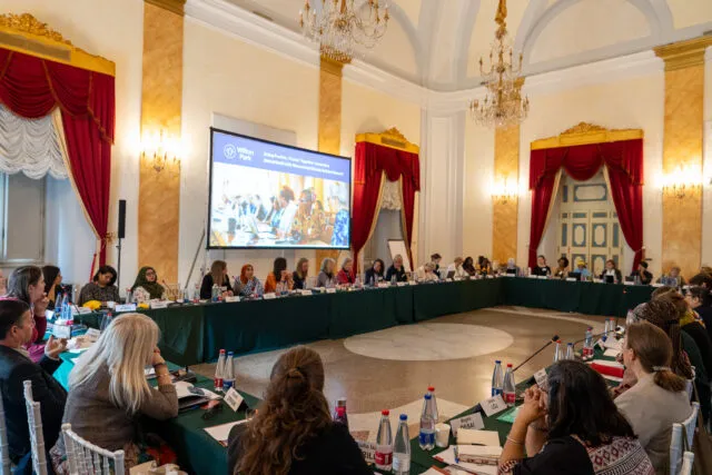 Wide shot of the conference table with participants sat around it.