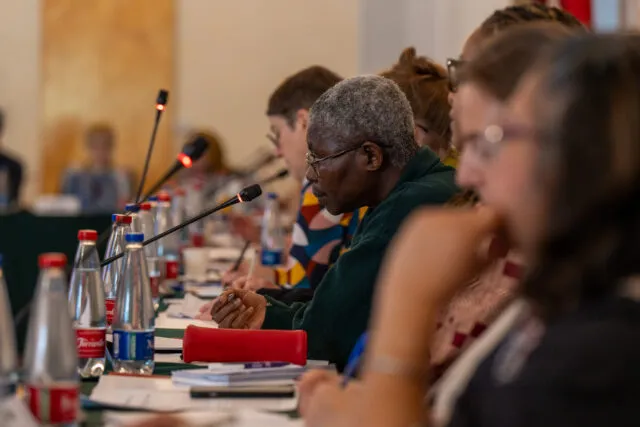 Participants are seated along the conference table