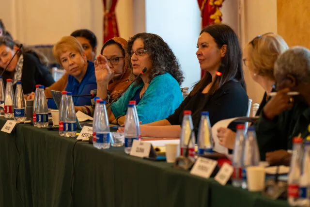 Participants are seated along the conference table