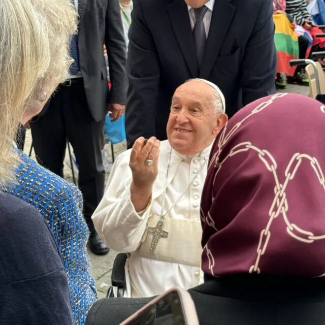 Pope Francis holds a dandelion badge.