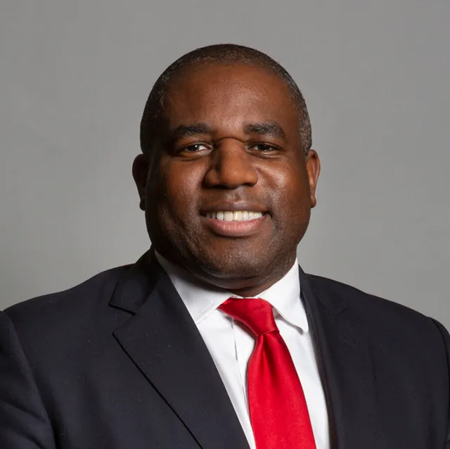 A portrait of David Lammy MP. He looks to camera and is wearing a red tie and dark suit.