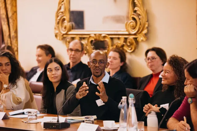 A close up shot of a delegate addressing the conference room with their hands outstretched.