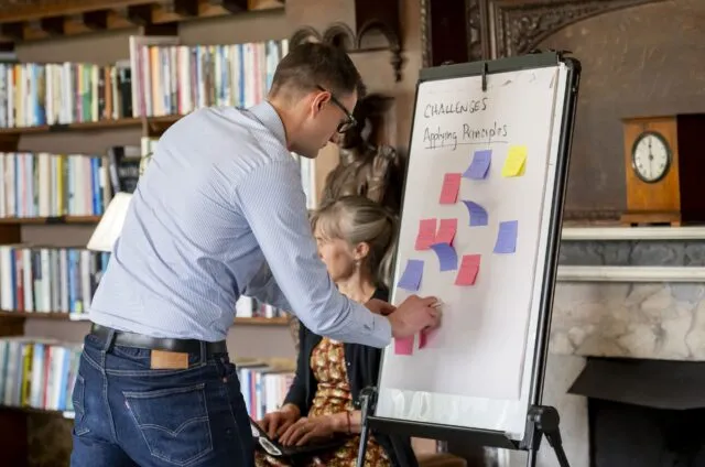 A participant adds coloured Post-it notes to a board