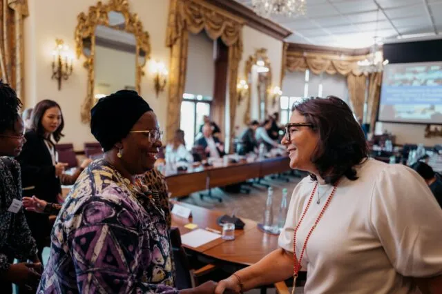 Two participants smile as they shake hands