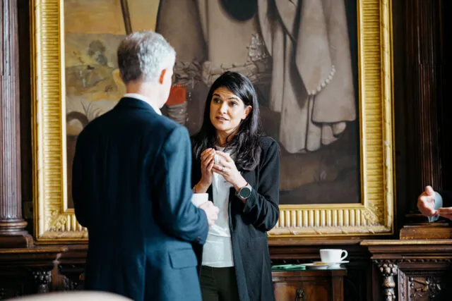 Two participants talk in front of a large oil painting