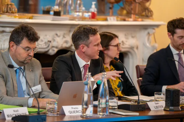 A participant speaks at the conference table