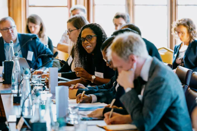 Kerry-Ann Barrett, Chief of the Cybersecurity Section with the Inter-American Committee Against Terrorism of the Organization of American States, wearing a dark blazer, speaking at the conference table during a Wilton Park dialogue.