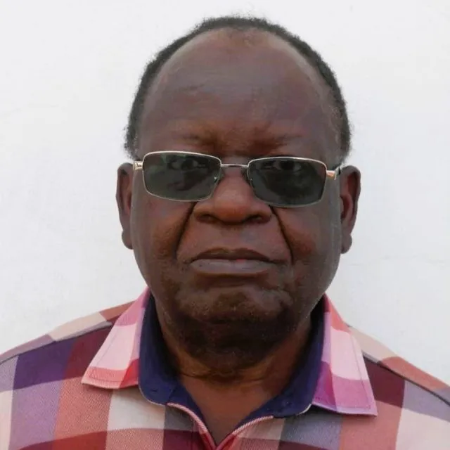 Dr Donald Chimanikire, Lecturer at at the Midland State University, Harare, Zimbabwe, looks at the camera wearing a checked shirt and glasses.