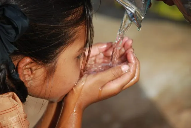 A child drinks water from their hands