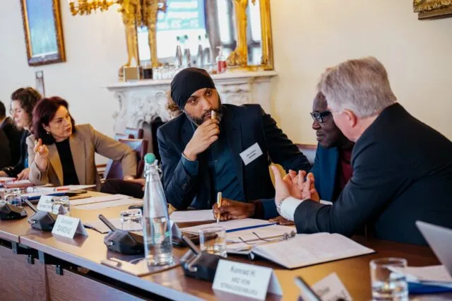 Three male participants deep in conversation at the conference table