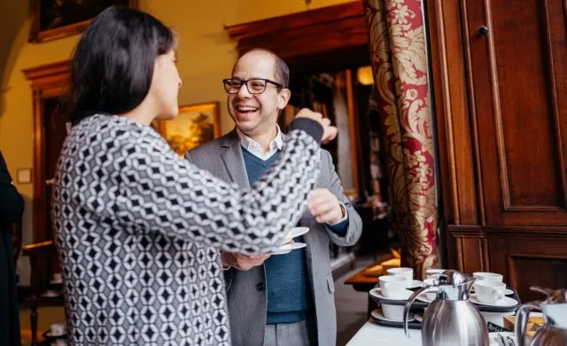 A participant smiles as he talks with a fellow participant as they collect their coffee cups