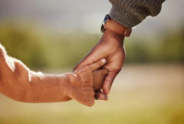 A parent and child hold hands.