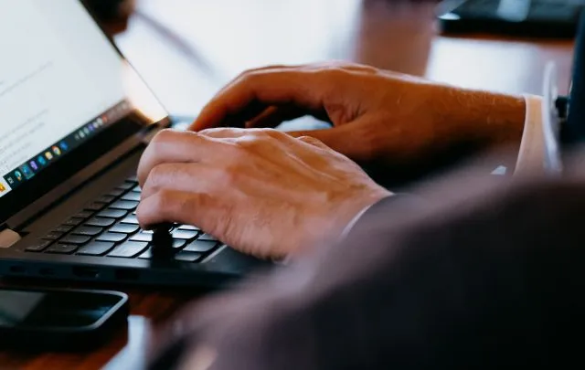 A pair of hands typing on a laptop