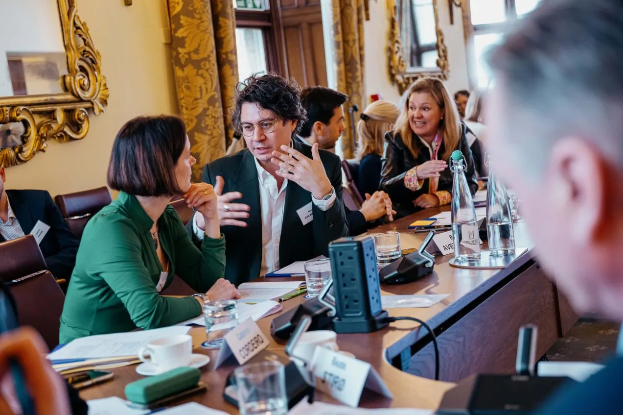 A group of participants talk as they sit at the conference table