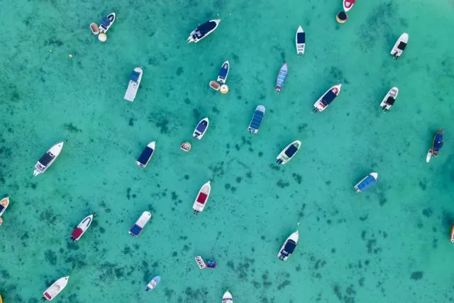 Aerial top view of Sailing and fish boats on turquoise clear tropical water of trou aux biches beach, Mauritus island, indian Ocean