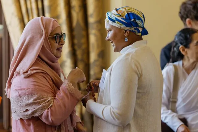 Two participants hold hands as they greet one another