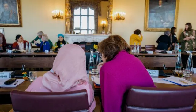 A back view of two participants at the Women, Faith and Climate network launch, in conversation at the conference table