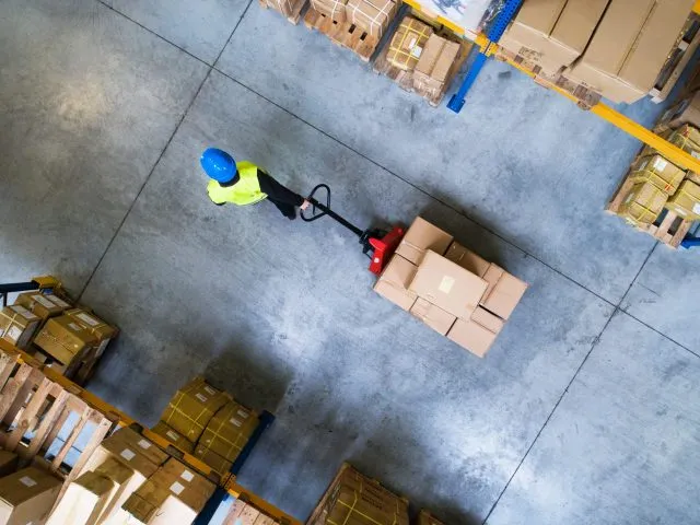 Aerial view of a worker pulling a pallet of boxes in a factory.