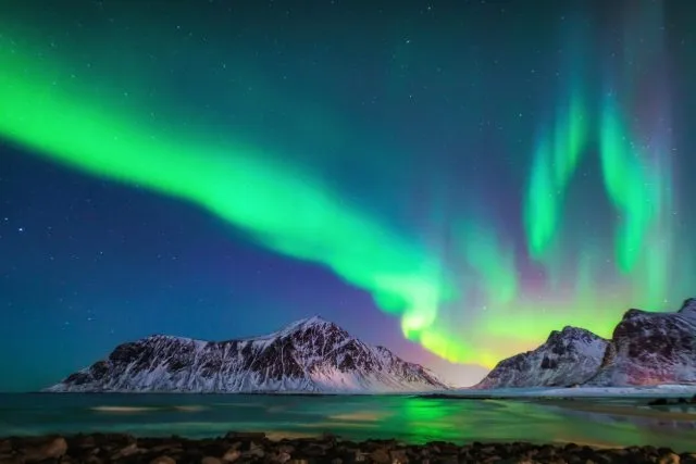 Aurora Borealis lighs the sky above snowy mountains in Sweden
