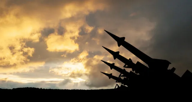 A silhouette of a missile system against a cloudy sky.