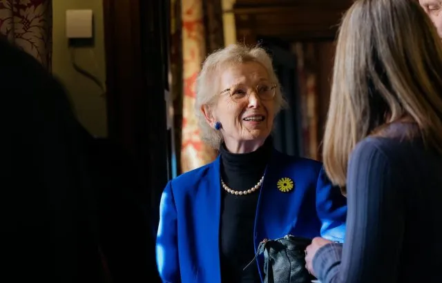 Mary Robinson standing and talking to another participant in the margins of a Wilton Park event. They are in deep discussion and the camera focuses on Mary's face.