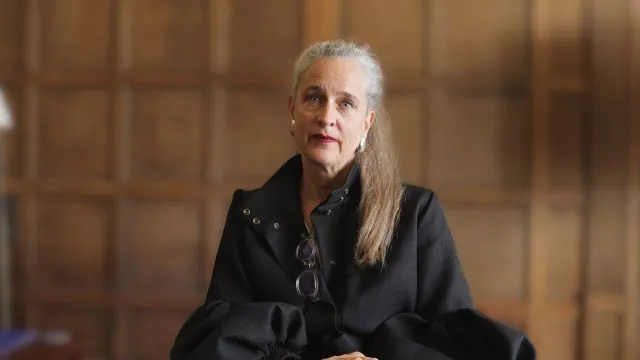 Bettina Schaller sits in front of a wood-panelled wall