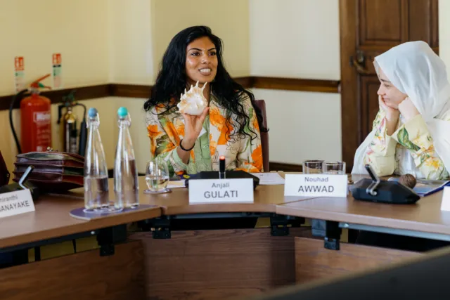 Anjali Gulati holds up a shell at the Wilton Park conference table