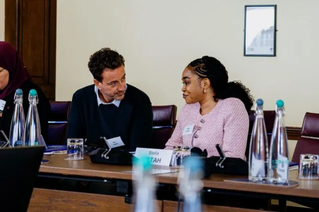 Two participants in conversation at the conference table