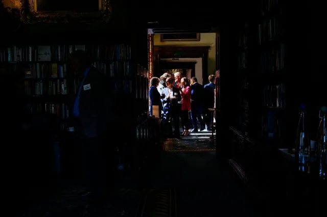 A group of people seen talking through a doorway in light and shade