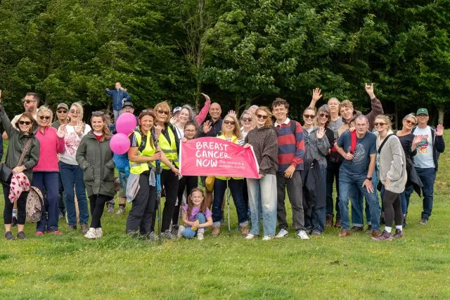 A group of walkers holding a Breast Cancer Now banner celebrate a successful walk