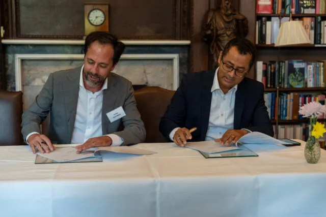 Two men read through documents for signing